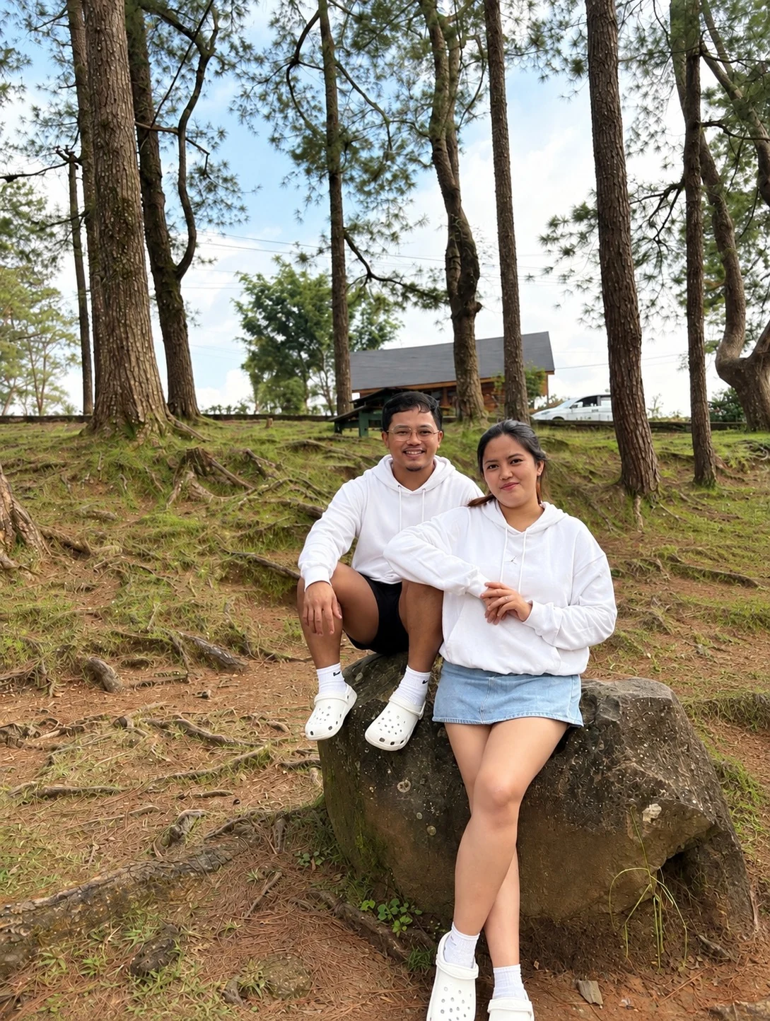 Francis and Jelyssa together by a large rock under the pine trees