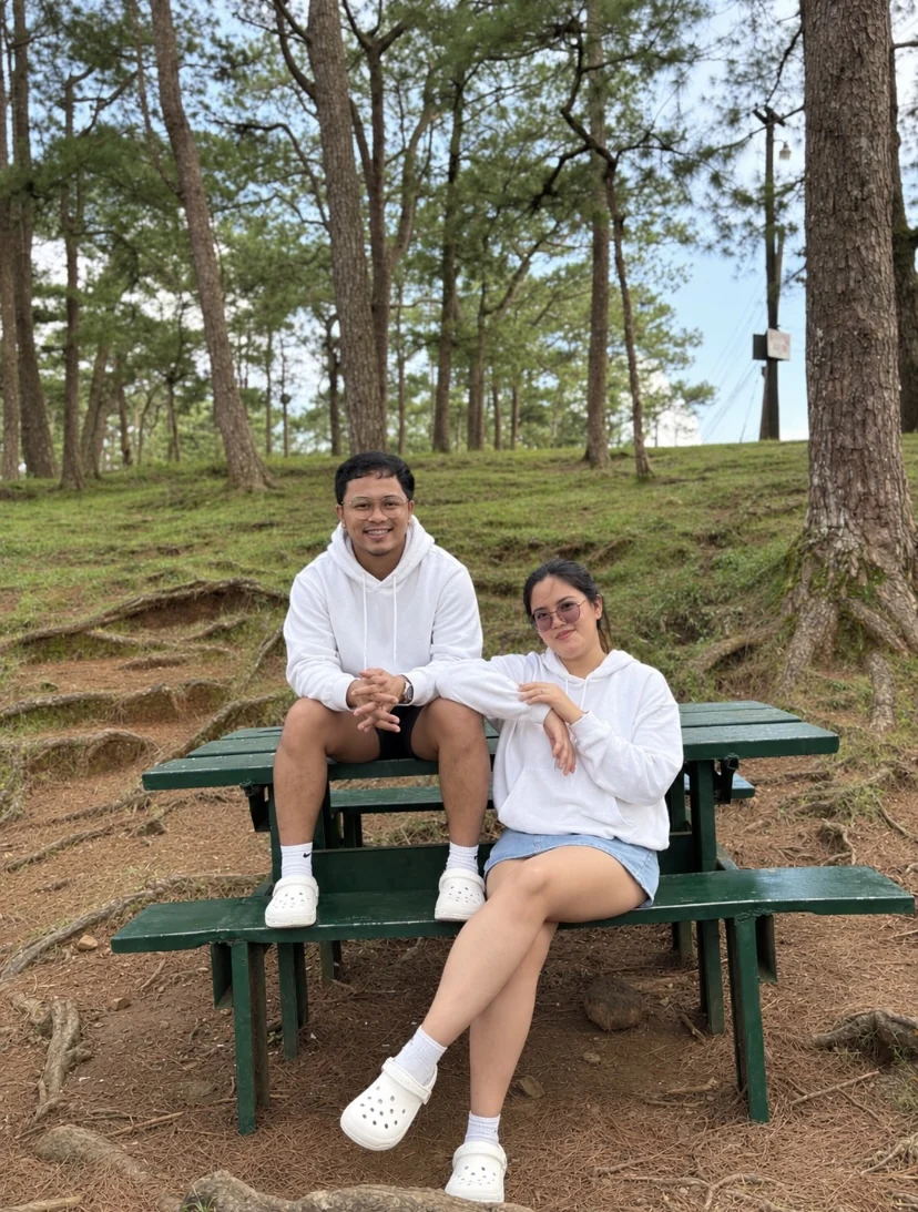 Francis and Jelyssa smiling together seated on a green picnic table